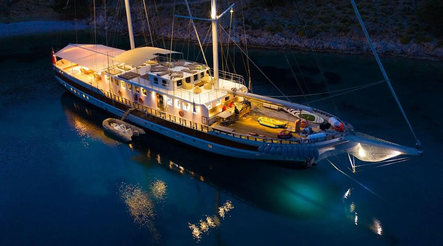 Yacht Tersane 8 at sunset showing sleek blue hull and illuminated deck
