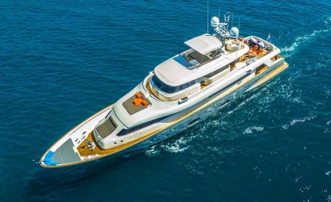 White modern yacht in open sea with sun loungers and seating area on the upper deck
