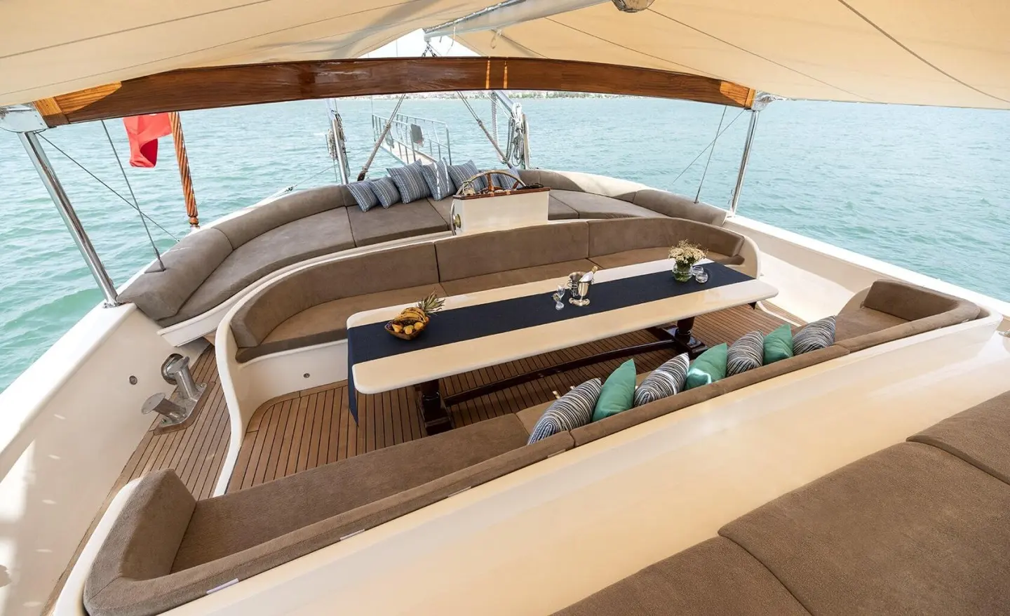 Curved sofa seating and table on a yacht lounge deck with sea view