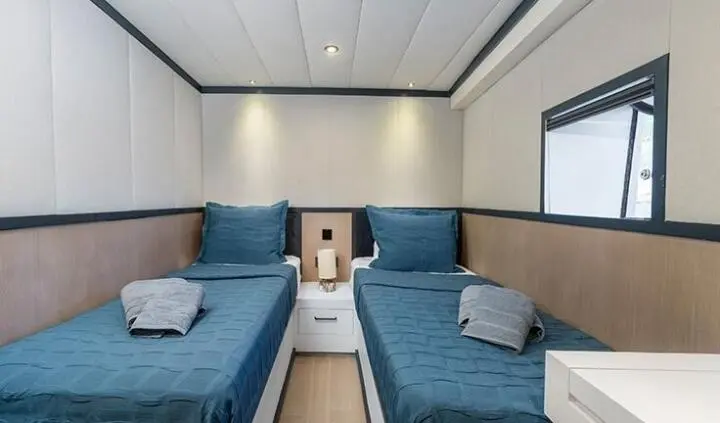 Twin cabin with two single beds, blue bedding, beige headboard wall panels