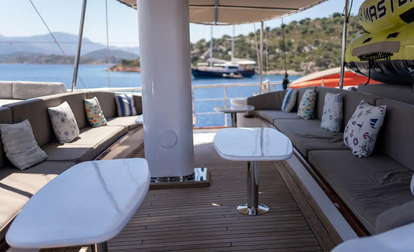 Shaded aft deck of Nevra Queen yacht with white seating and table on wood deck
