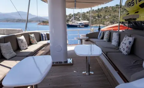 Shaded aft deck of Nevra Queen yacht with white seating and table on wood deck