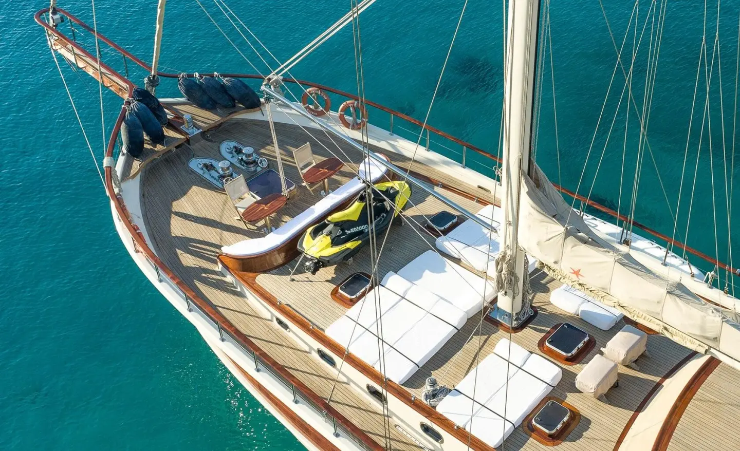 Gulet Estrella De Mar bow deck with coiled rope, benches, and sunlit teak, turquoise sea