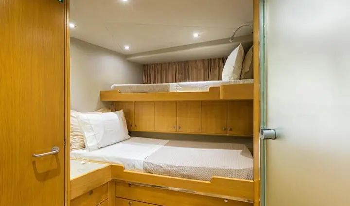 Interior bunk cabin on yacht with wooden storage and bedding setup