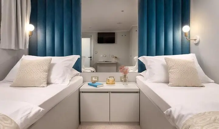 Twin cabin with two single beds separated by a shared nightstand on a yacht interior