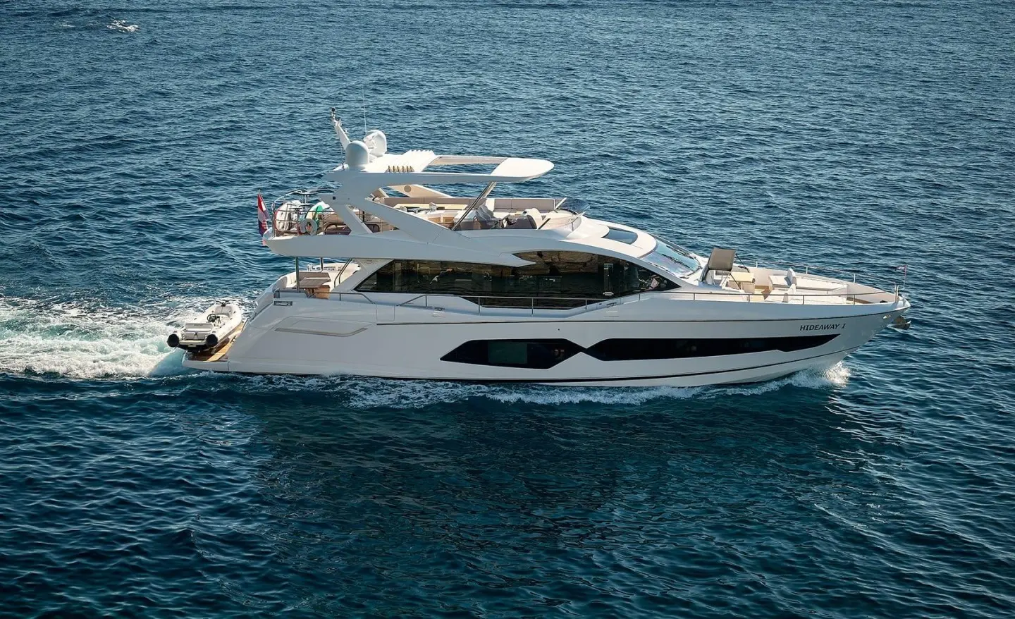 Yacht named Hideaway cruising on calm blue water with sunlit hull
