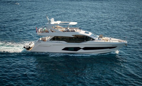 White luxury motor yacht cruising in open sea, side windows and multi-level upper deck