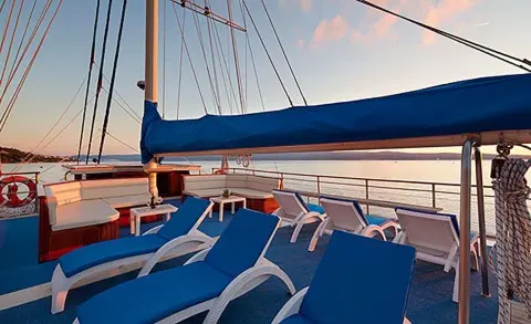 Sun loungers with blue cushions on a luxury sailing yacht deck at sunset