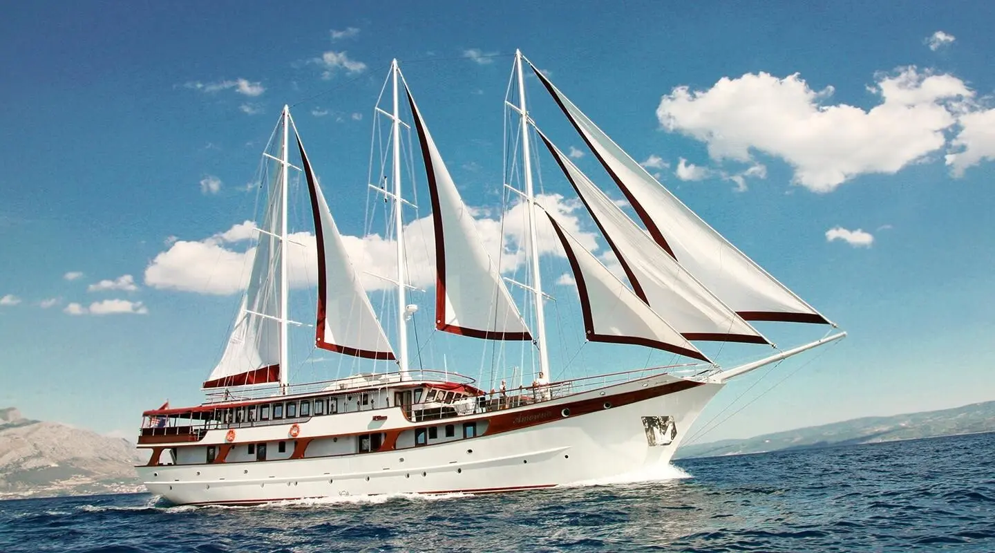 Amorena luxury sailing yacht with multiple white sails unfurled on blue sea