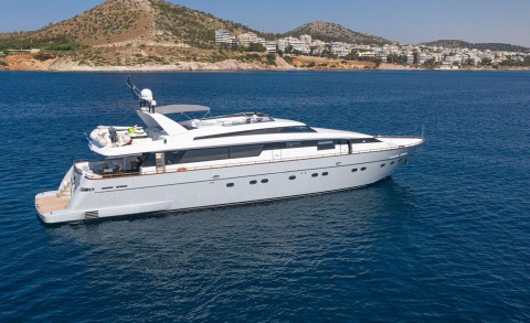 Grace luxury motor yacht anchored near a rocky coastline with white buildings in the background