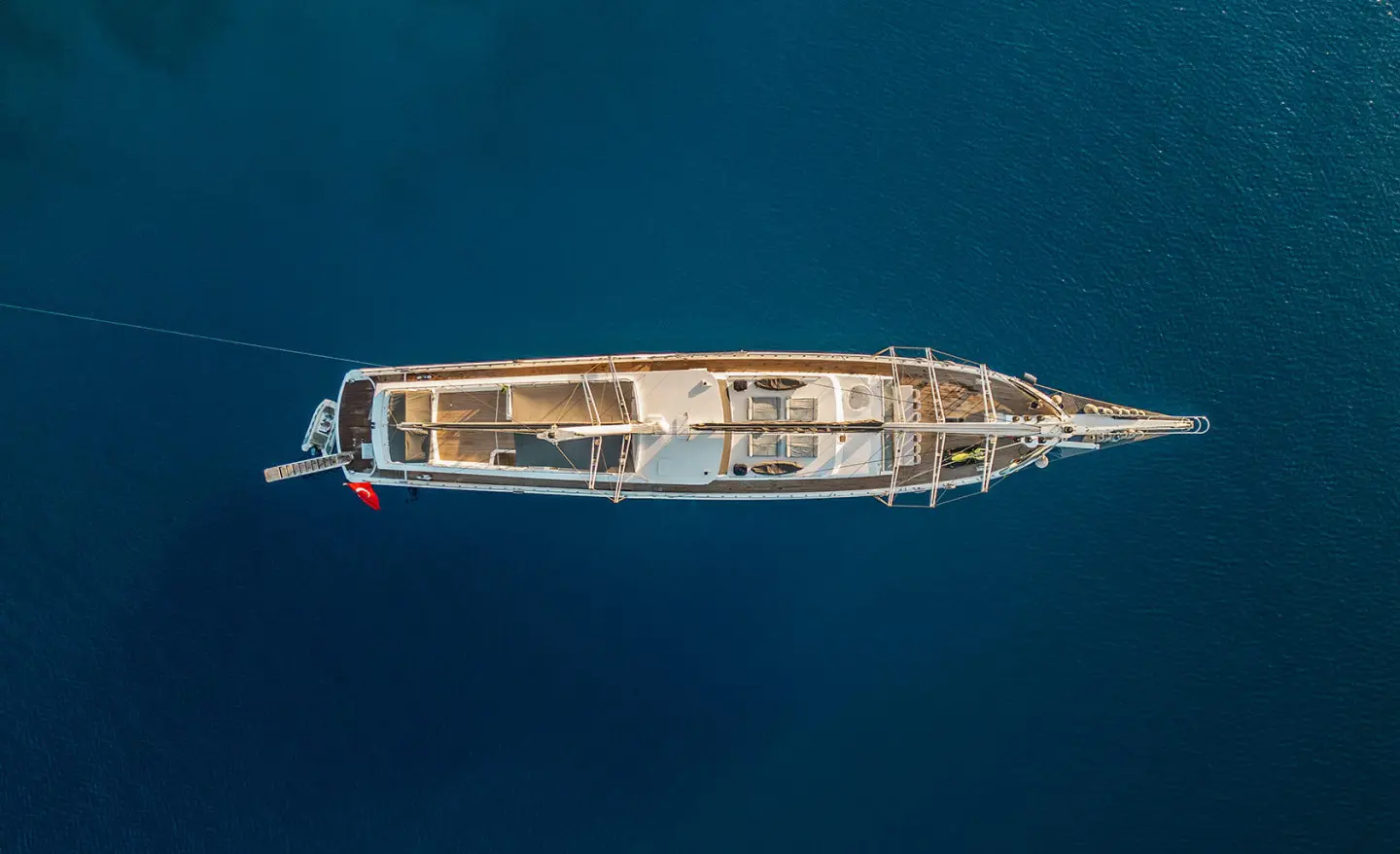 Top-down view of a sleek yacht named Esma Sultan sailing calm blue water at sunset