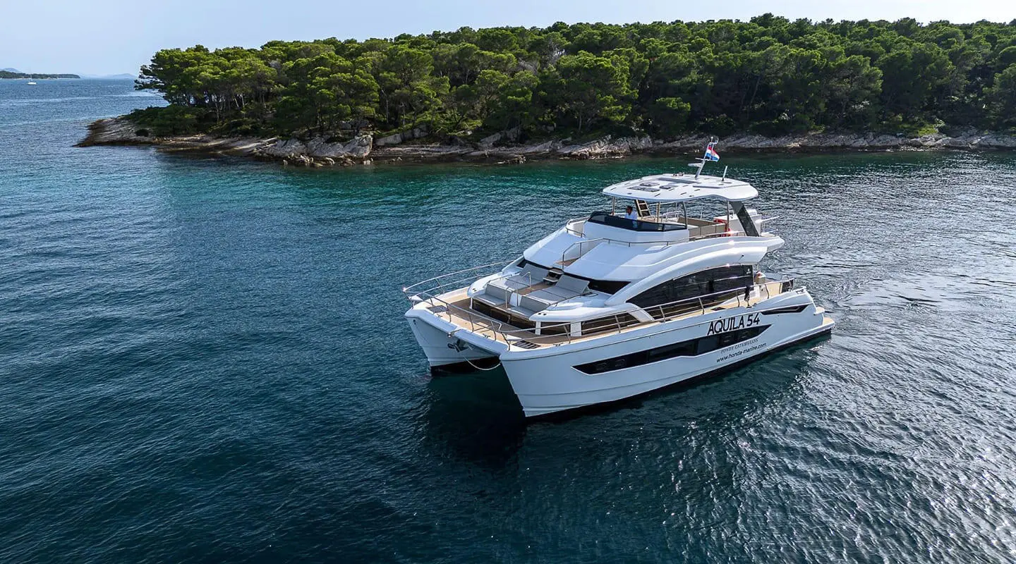 Luxury motor yacht named By My Side docked in calm blue water near a tree-lined shore