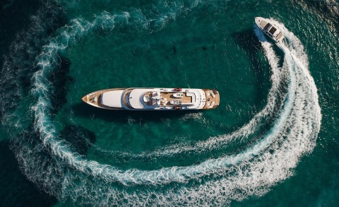 Aerial view of a large motor yacht sailing on turquoise sea, seen from above