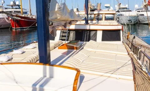 Sun loungers with striped cushions on an open deck, other yachts in the marina visible