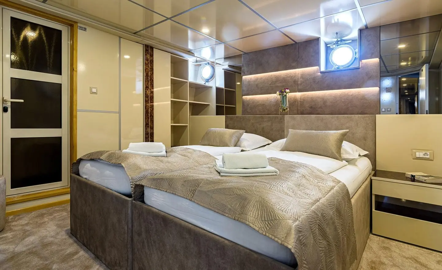 Luxury motor yacht Melody cabin with large bed, warm lighting, and wooden cabinetry