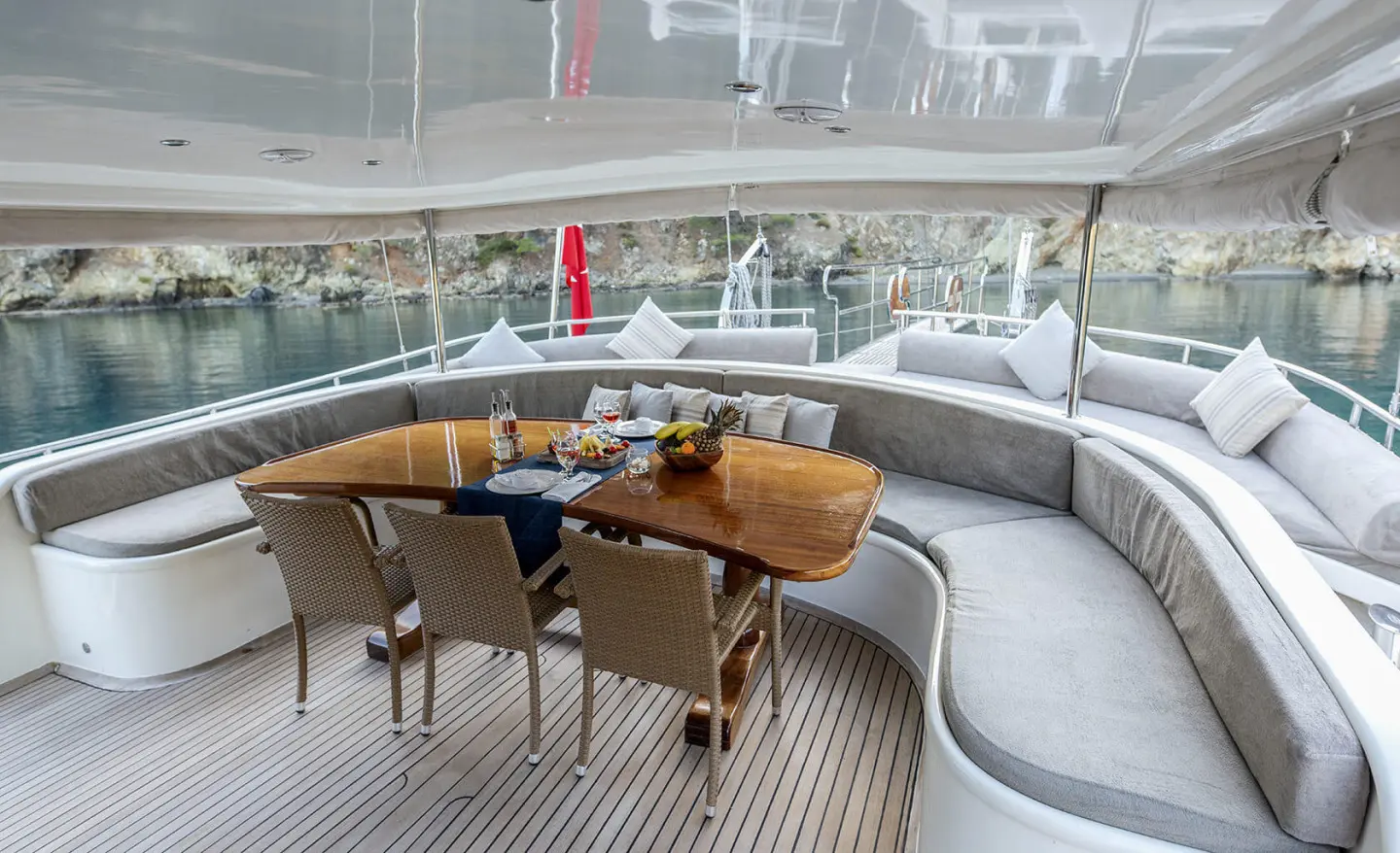 Kayhan 4 yacht on sunlit deck with wicker seating and glass railing