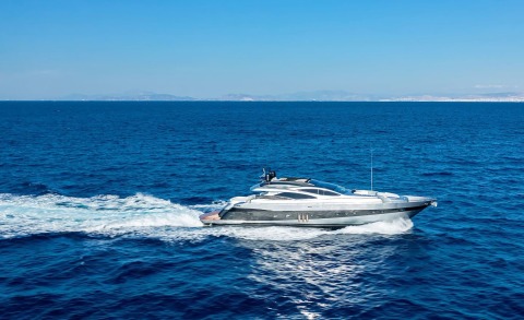 Silver motor yacht cruising on open sea with wake behind it