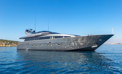Summer Fun luxury motor yacht anchored offshore with sleek dark hull and clear blue sky