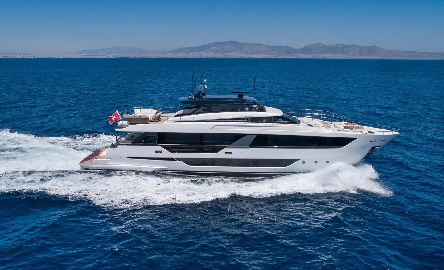 Spica motor yacht cruising on blue sea, white wake, clear sky