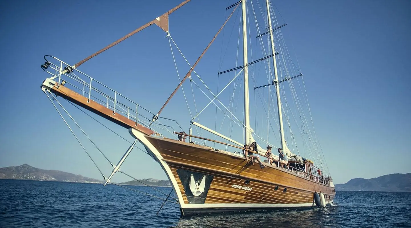 wooden hull gulet sailing yacht with guests on deck at sea