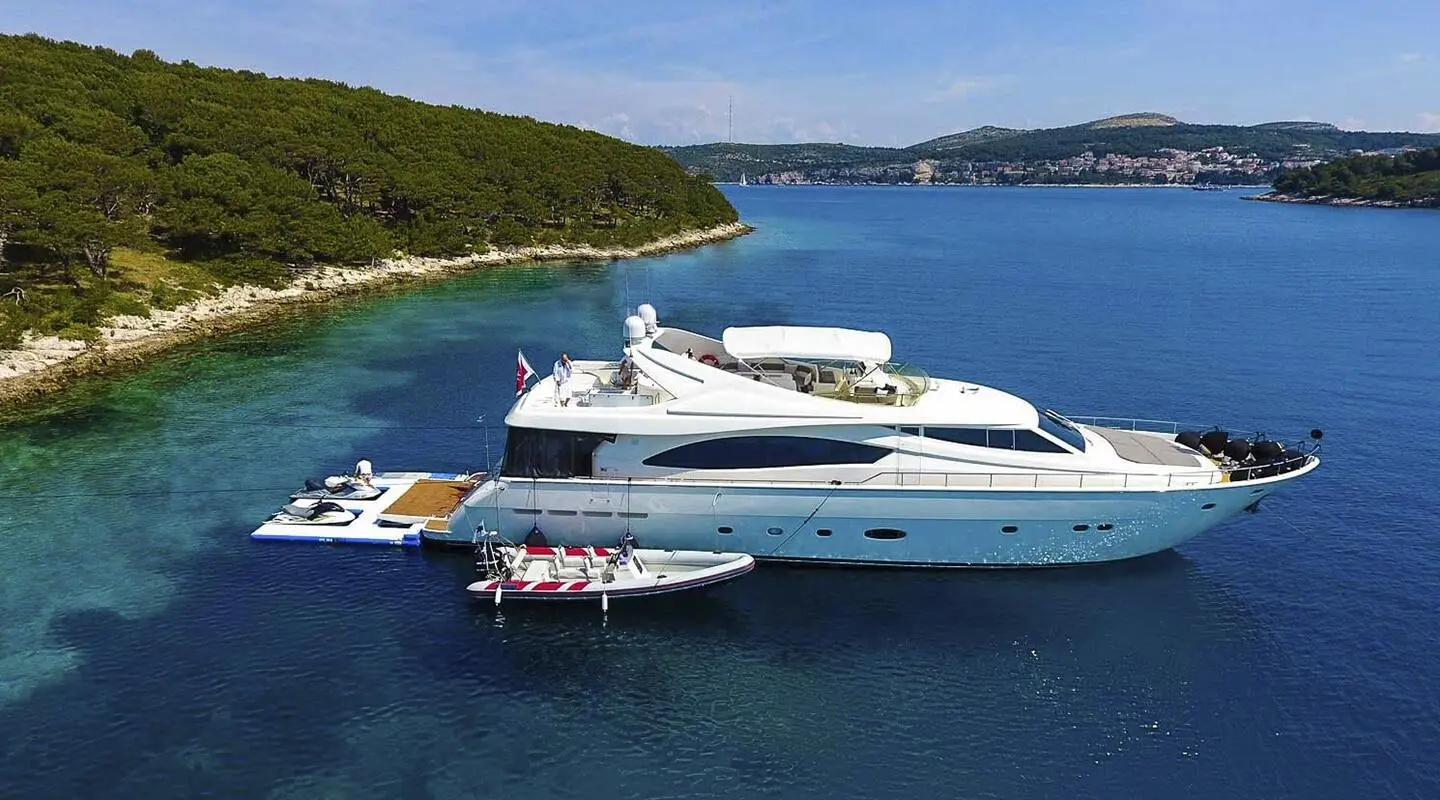 Miss Katariina luxury motor yacht anchored near coastline with small dinghy nearby
