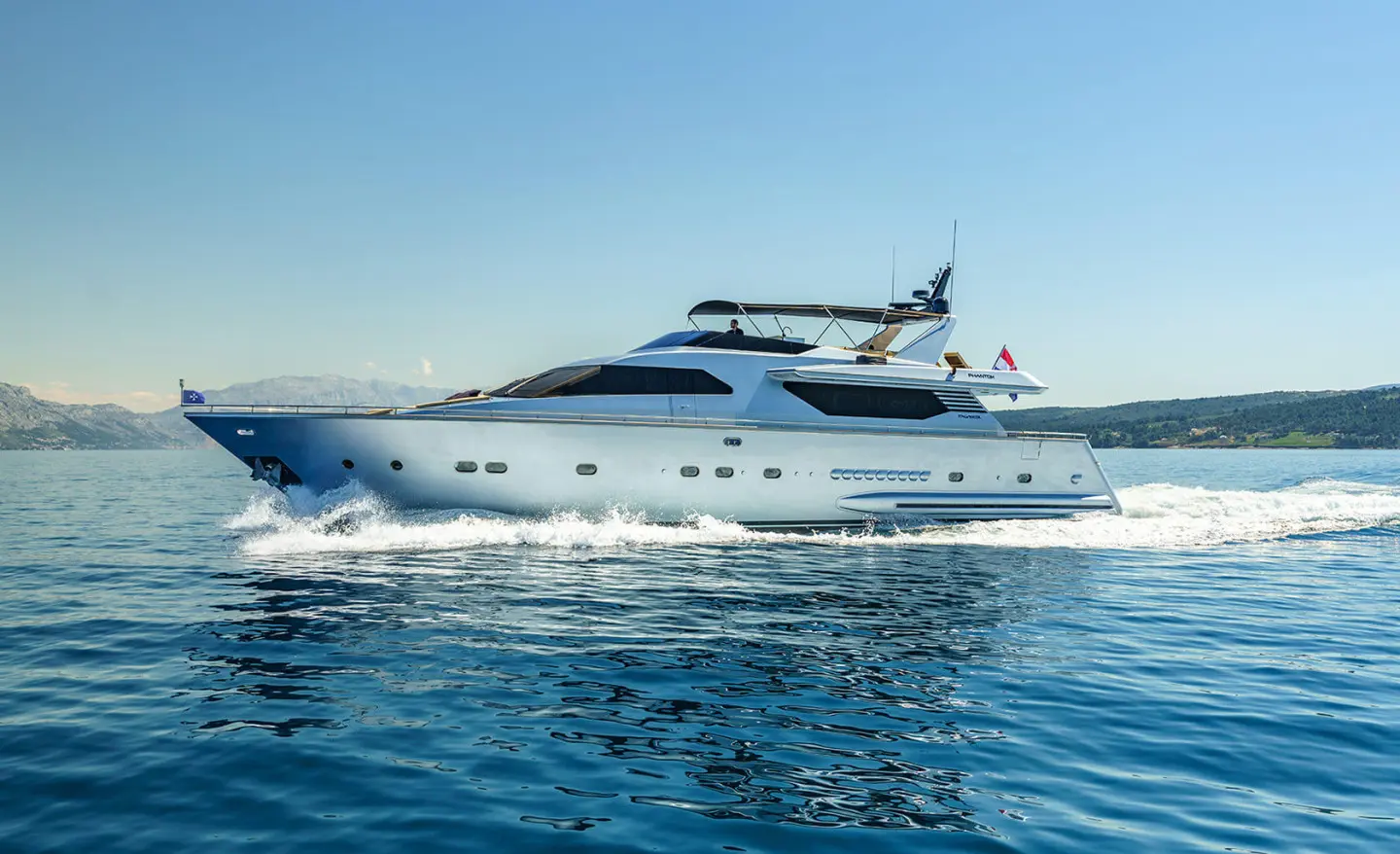 White motor yacht cruising on open sea with waves splashing at bow