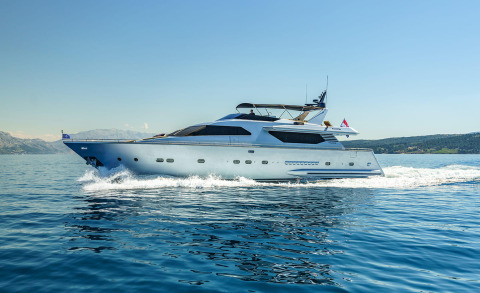 White motor yacht cruising on open sea with waves splashing at bow