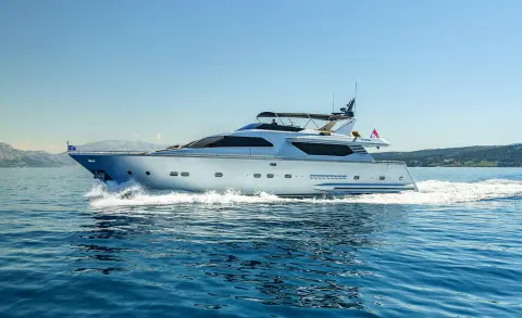 White motor yacht cruising on open sea with waves splashing at bow