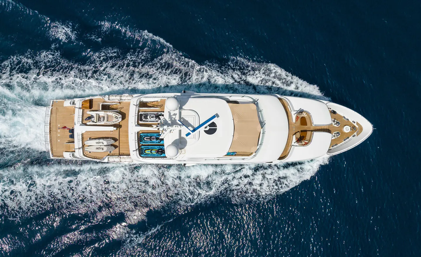 Top-down view of Serenity yacht cruising with wake in clear blue water