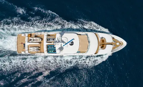 Top-down view of Serenity yacht cruising with wake in clear blue water