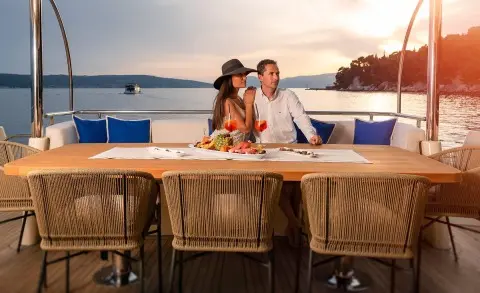 Grace yacht aft deck, sunlit seating area with two people lounging aboard