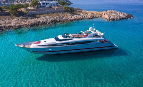 Glaros luxury yacht anchored in turquoise shallows near rocky coastline