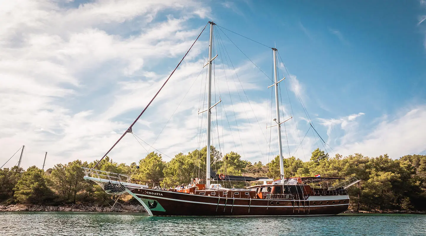 Luxurious sailing yacht anchored at sunset with masts and blue sky