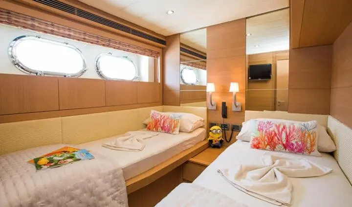 Twin cabin aboard Salt yacht with two single beds and porthole windows