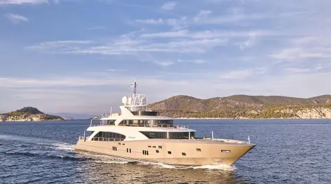 Luxury yacht La Pellegrina 1 moored on calm blue water with coastal hills behind