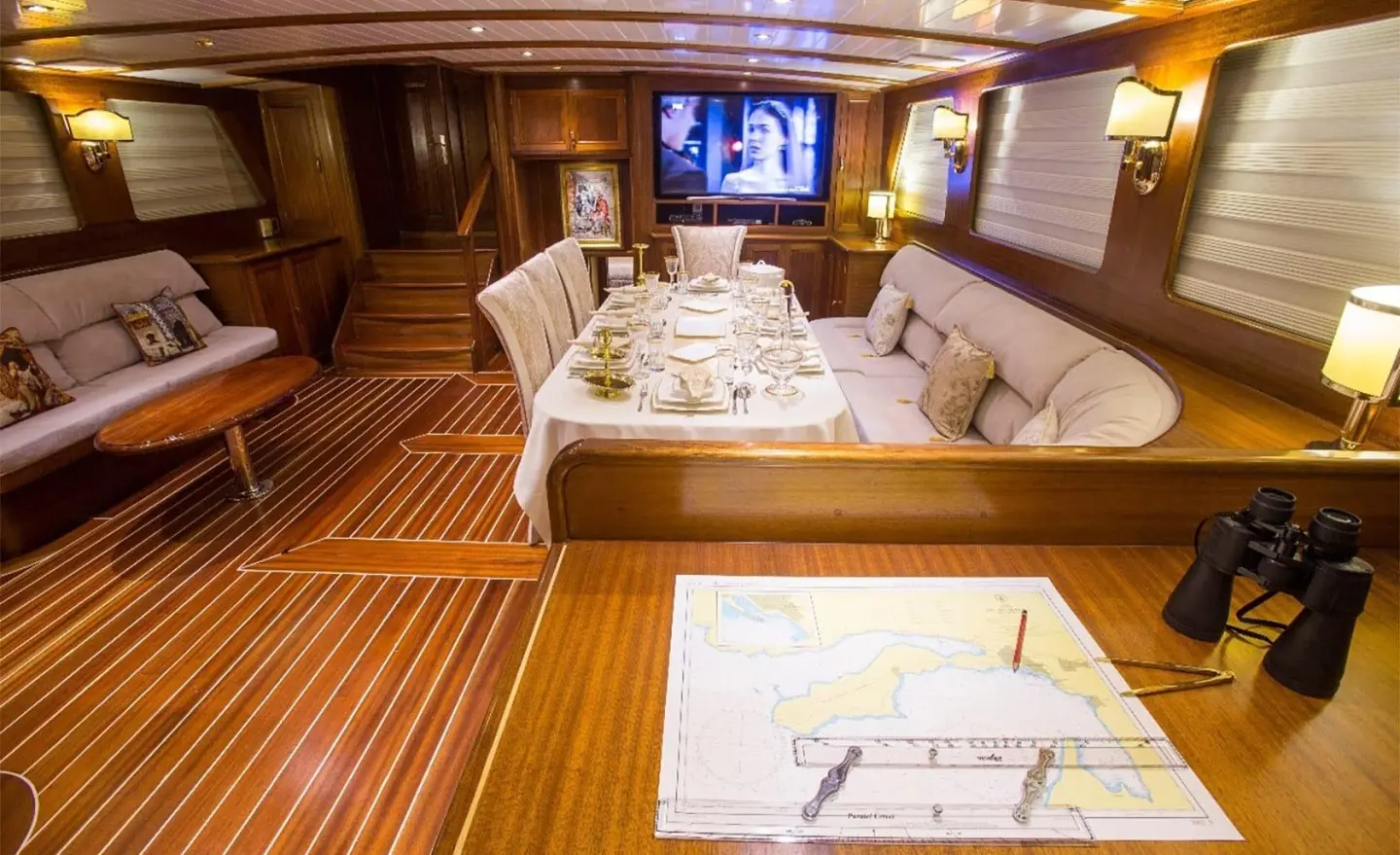 Interior of luxury gulet yacht Ece Berrak with wood deck, seating, and table setup at sunset