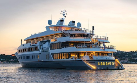 Sunset view of the luxury Marquise yacht anchored on calm water with glowing windows and distant shoreline