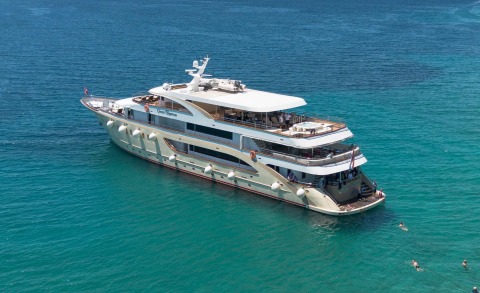 Queen Eleganza luxury yacht anchored in turquoise waters, sunlit deck lounge area visible
