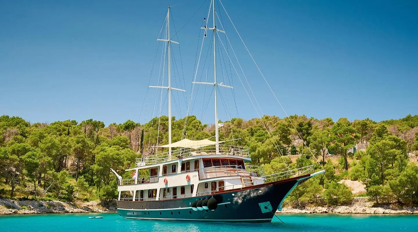 Luna sailing yacht anchored near green coastline at sunset with blue water