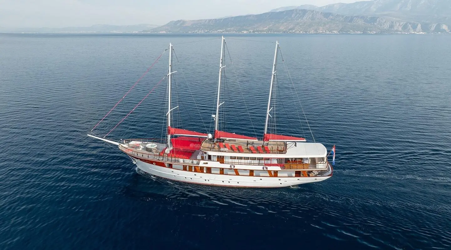 Barbara yacht with red and white hull sailing on calm blue sea