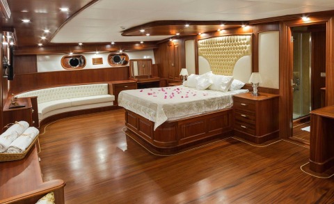 Master bedroom with rich wood paneling, upholstered bed, and bedside lamps inside a yacht cabin