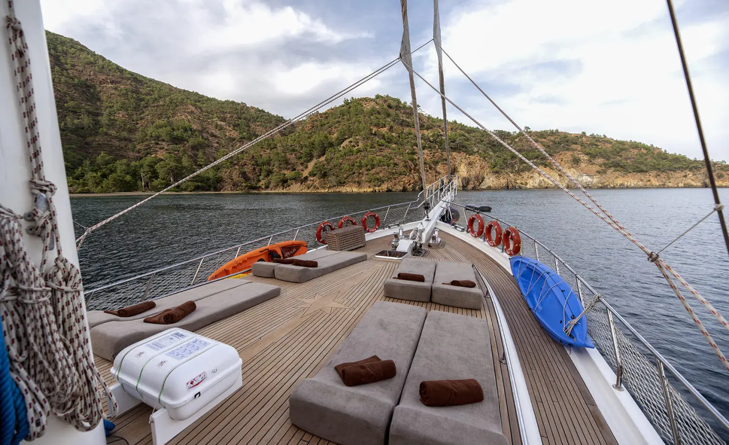 Kayhan 3 yacht at a harbor with sunlit shingles and small boats on calm water