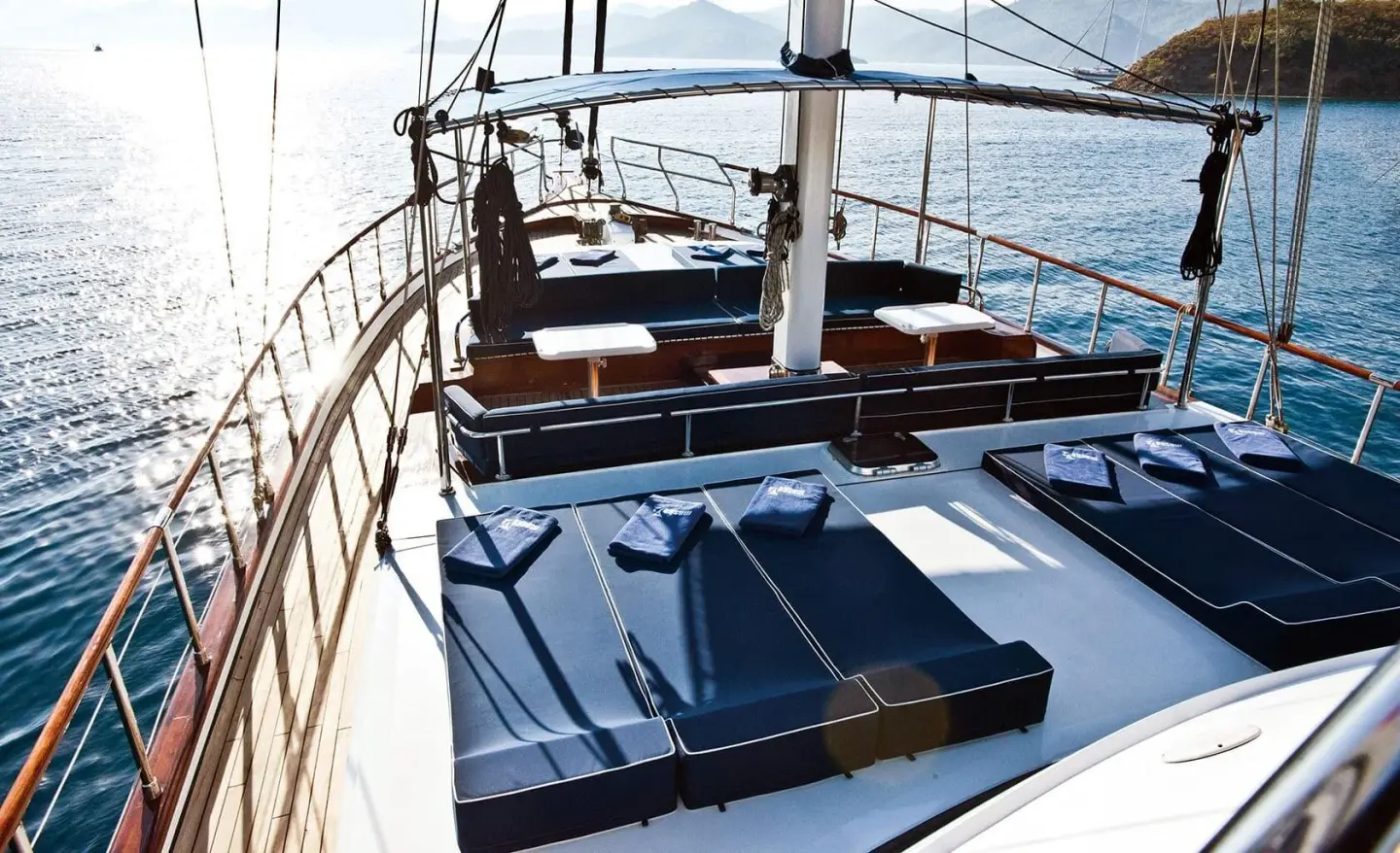 Maske 2 yacht deck with blue sun pads and sailing rig at sunset