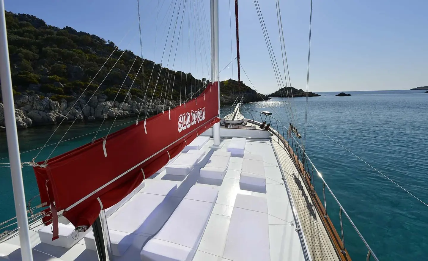 Blu Dream sailing yacht on clear blue sea with red sail cover and white deck seating