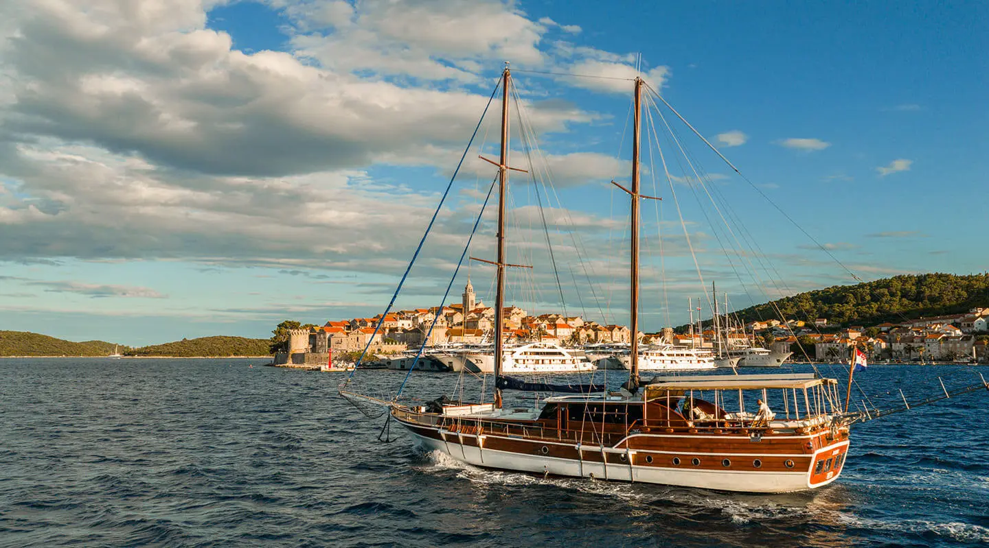 Gulet Eleganza sailing yacht on open sea near a harbor town