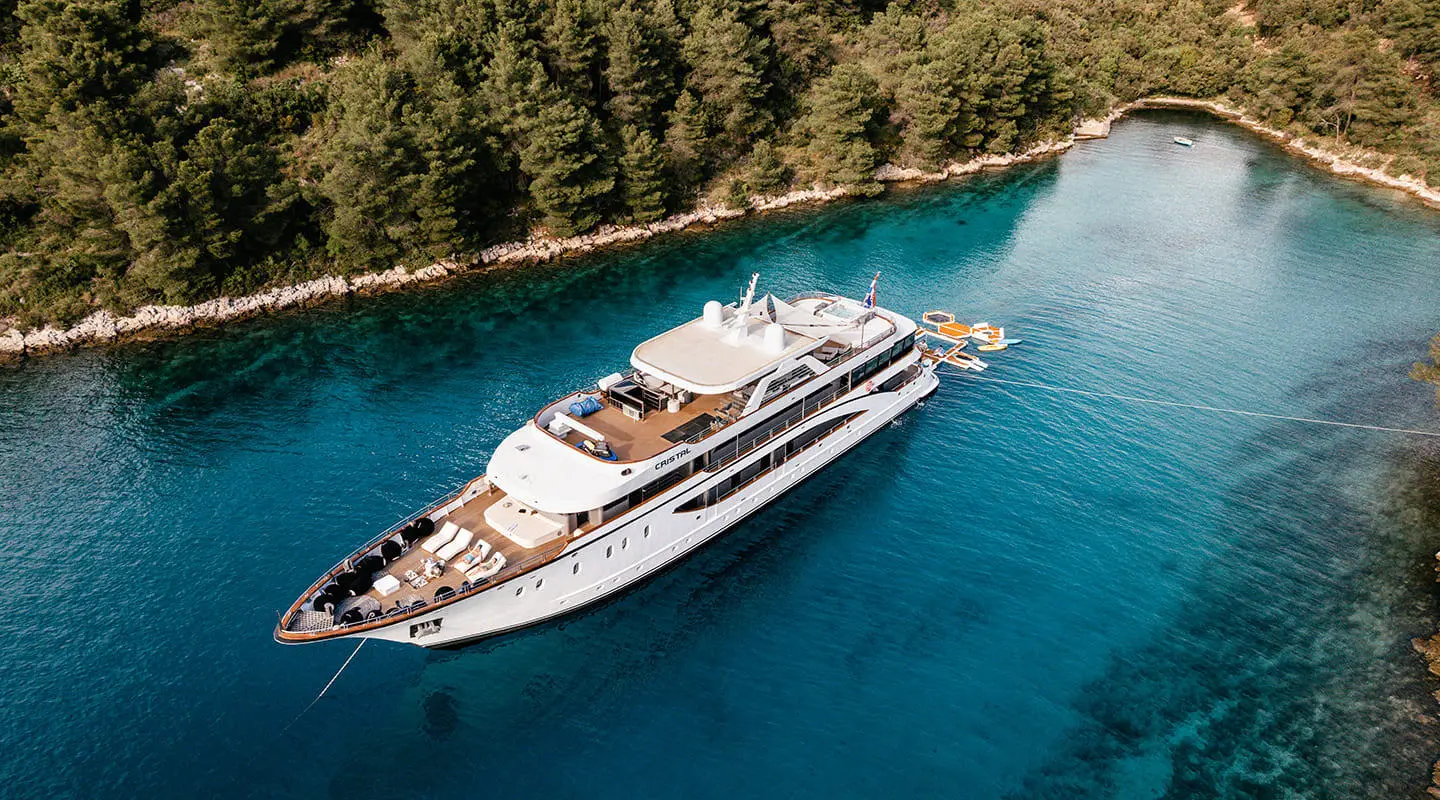 Cristal yacht anchored in turquoise bay, white hull, sunlit water