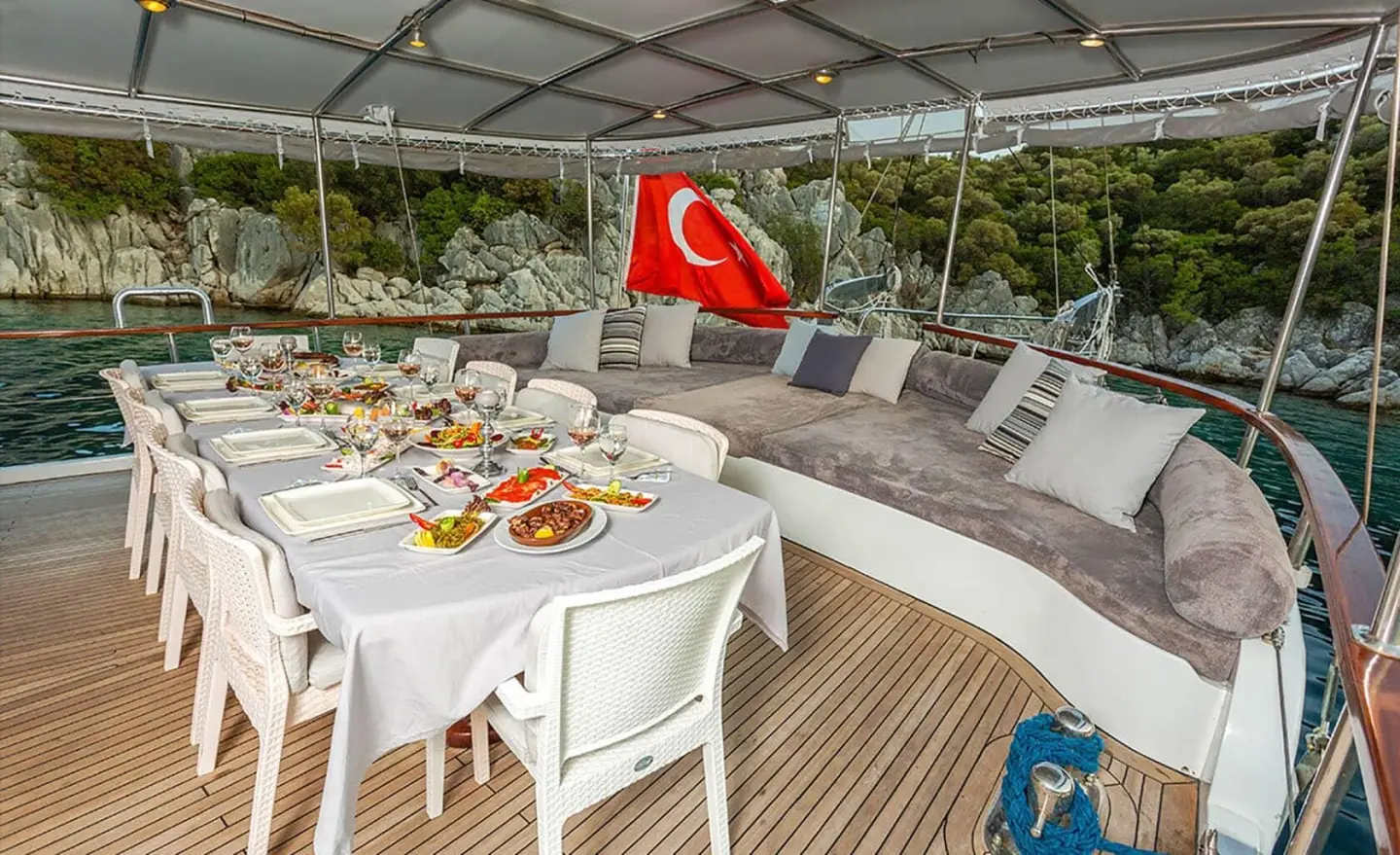 Sunset on a luxury gulet yacht deck with a dining table set under a canopy