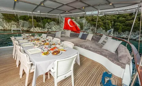 Sunset on a luxury gulet yacht deck with a dining table set under a canopy