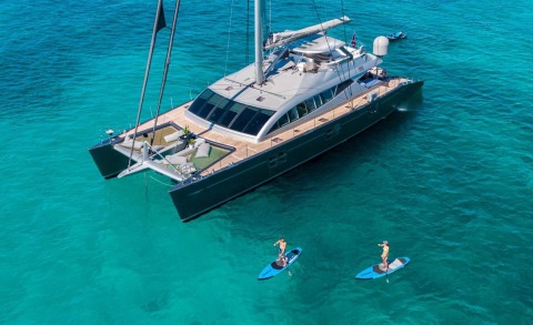 Cartouche luxury yacht anchored in turquoise waters with deck loungers and a forward tender on the bow
