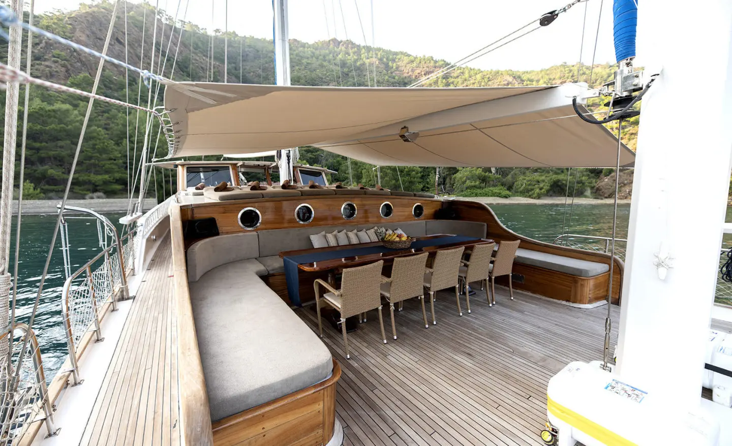 Kayhan 8 yacht charter on deck with wooden table seating under shade at sunset